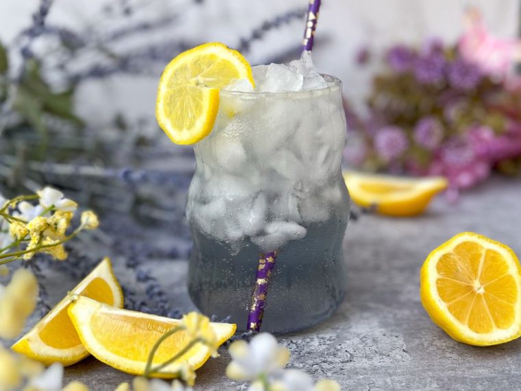 a garden party mocktail of sparkling lavender lemonade styled with fresh lemon slices and lavender flowers