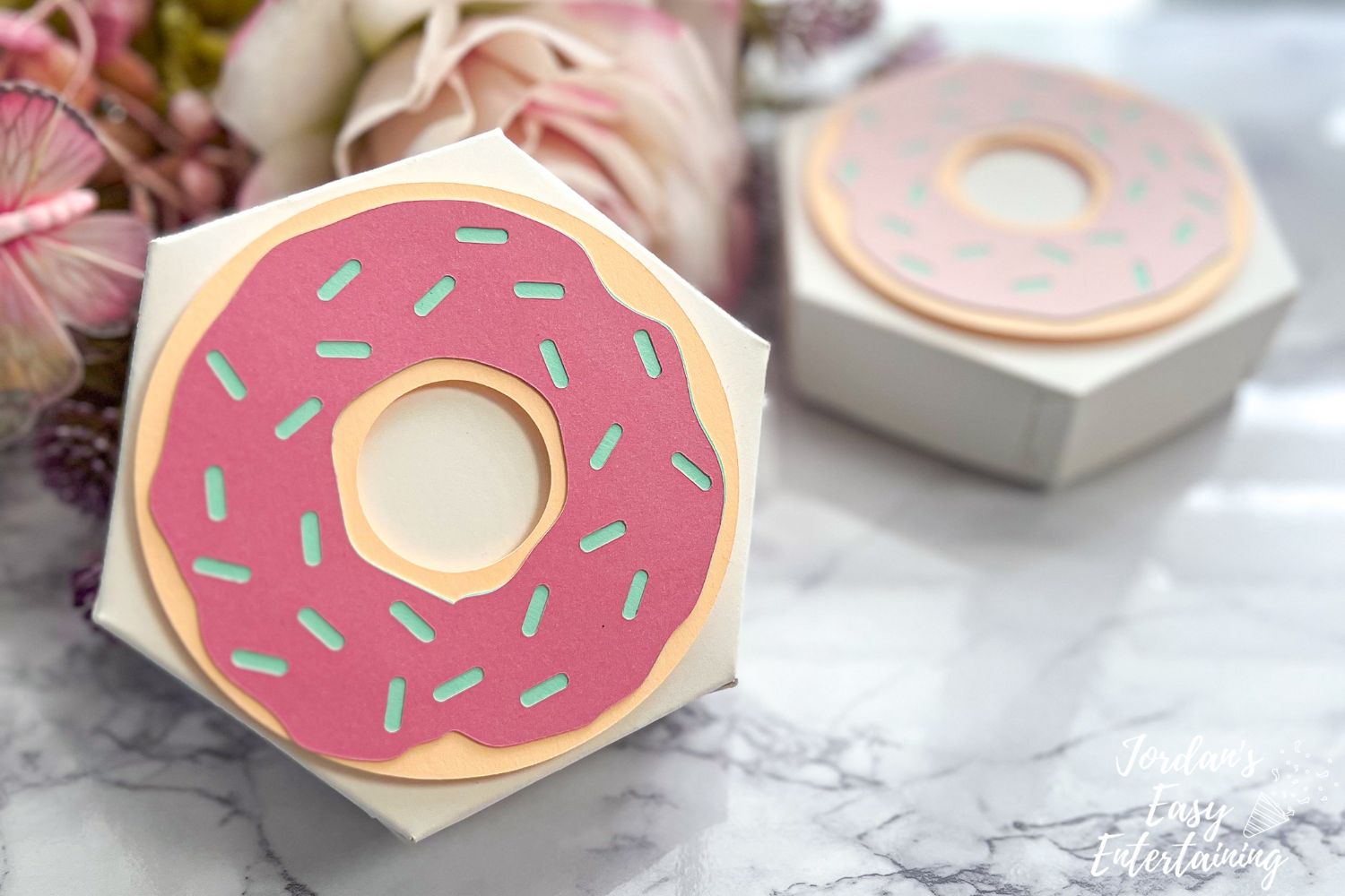Pastel pink DIY donut party favor box made with Cricut, styled with sprinkles and kraftboard, perfect for birthday or brunch party favors.