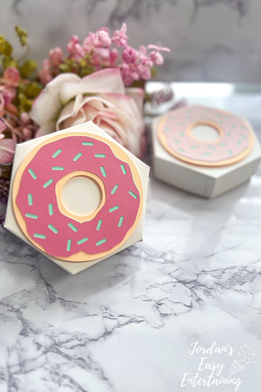 Pastel pink DIY donut party favor box made with Cricut, styled with sprinkles and kraftboard, perfect for birthday or brunch party favors.