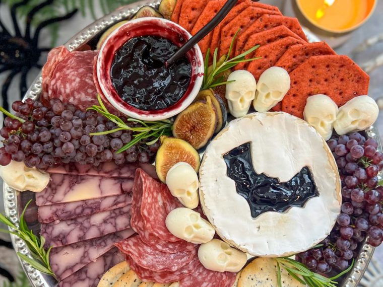 Halloween charcuterie board with skull cheese and bat Brie styled with candles and dark accents for a vampire-themed party